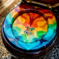 A colorful toilet seat featuring a Hogwarts crest, designed with vibrant shades that create a kaleidoscopic effect, reflecting the whimsical spirit of the magical world.