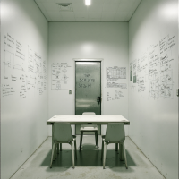 A stark white room with formulas and notes covering the walls, containing a simple table and chairs, representing the only space shielded from SCP-3125’s pervasive influence.