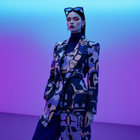 A model stands confidently in a patterned suit against a vibrant blue and purple background, embodying the idea that every choice shapes our identity.