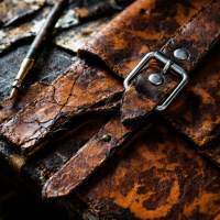 An aged leather portfolio with a metal buckle lies on a textured surface, accompanied by a vintage pen, evoking the sentiment of the quote, Nothing personal, but I don’t want to see you again.