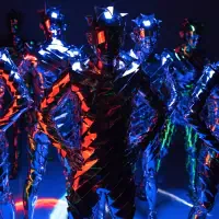 Figures clad in sharp, hard metal armor with layered plates and distorted shapes stand posed under blue and red lighting, their forms blending machine and body.